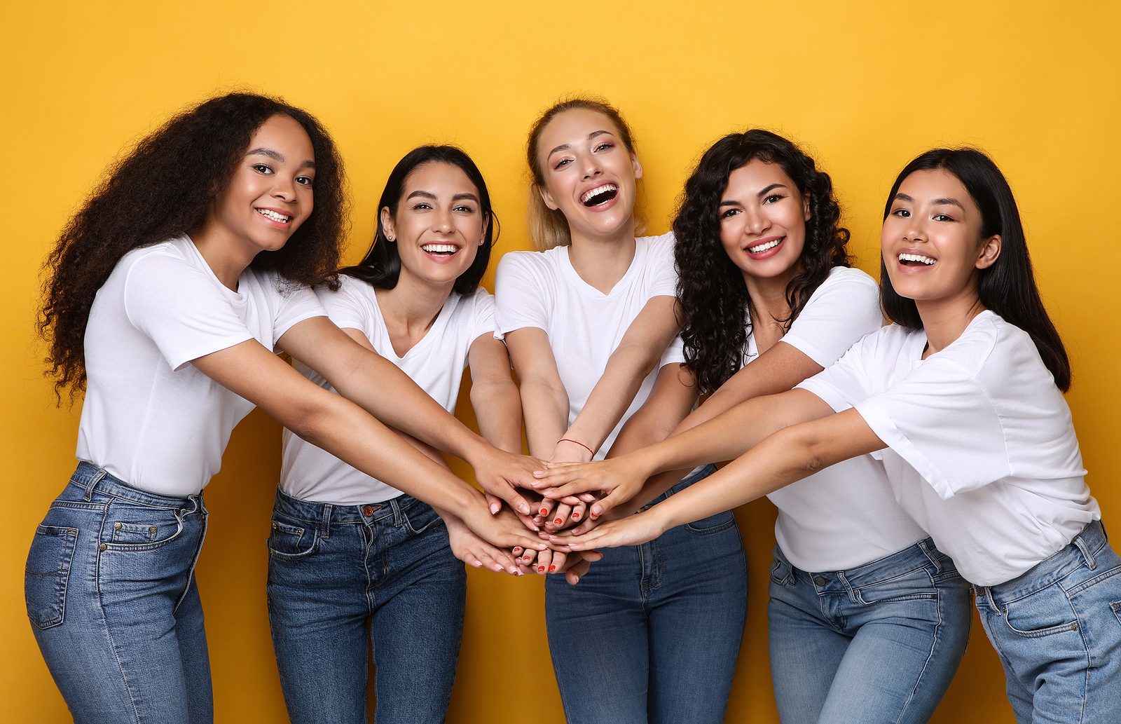 Group Of Five Happy Multiethnic Women Holding Hands Posing On Ye