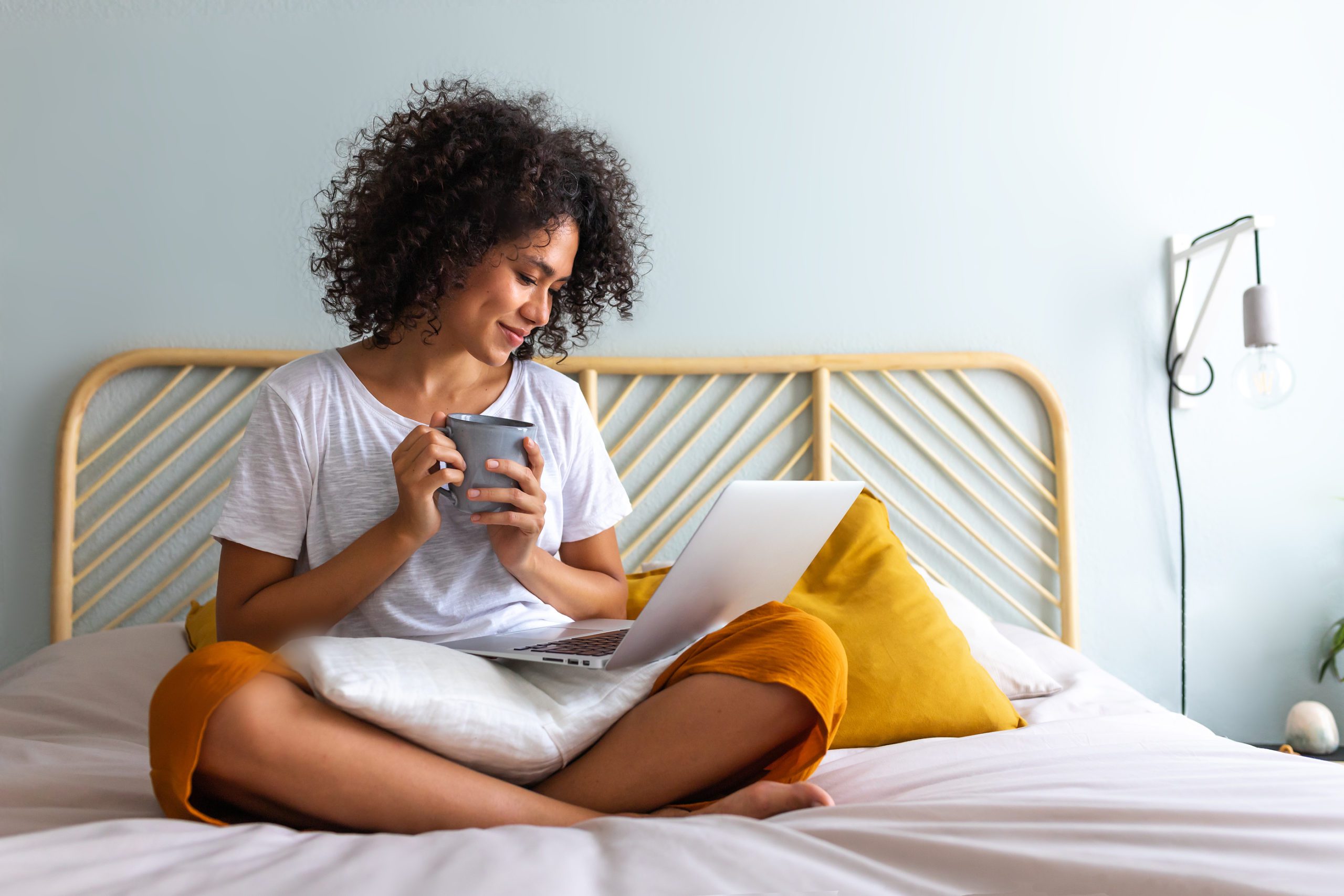 Cozy At Home. African American Woman Sitting On Bed Drinking Cof